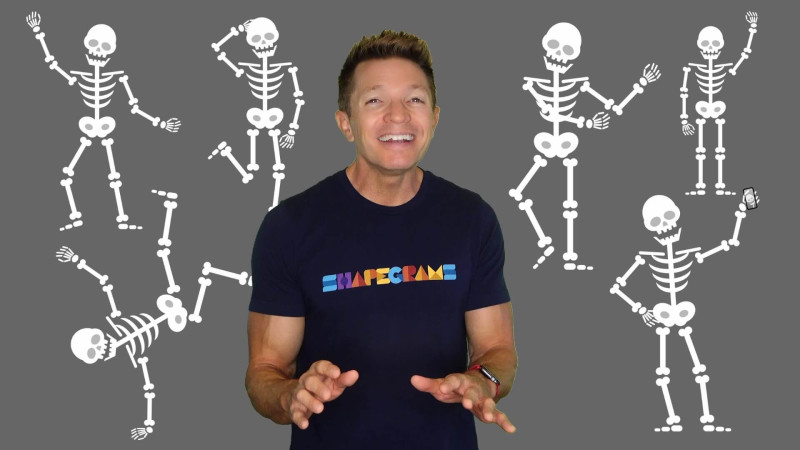 Photo of Tony surrounded by drawing of skeletons striking vaious poses Photo of Tony surrounded by drawing of skeletons striking vaious poses